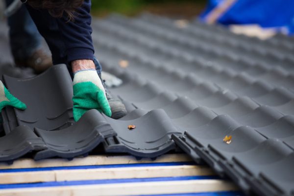 Dakdekker legt donkere dakpannen op houten panlatten