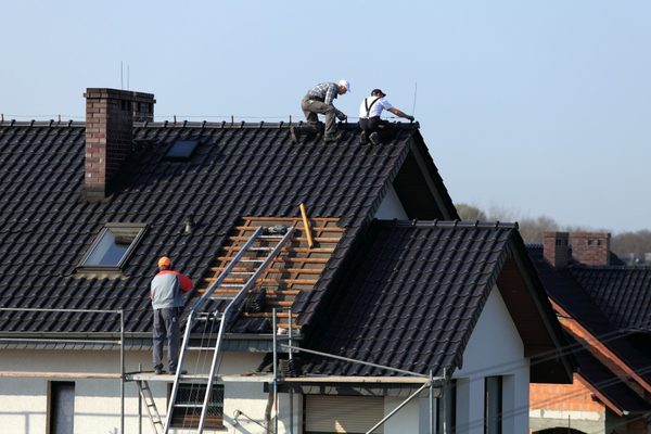 Dakdekkers werken aan een pannendak met steiger en daklift