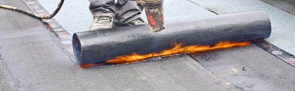 Dakdekker brengt bitumen dakbedekking aan met een brander