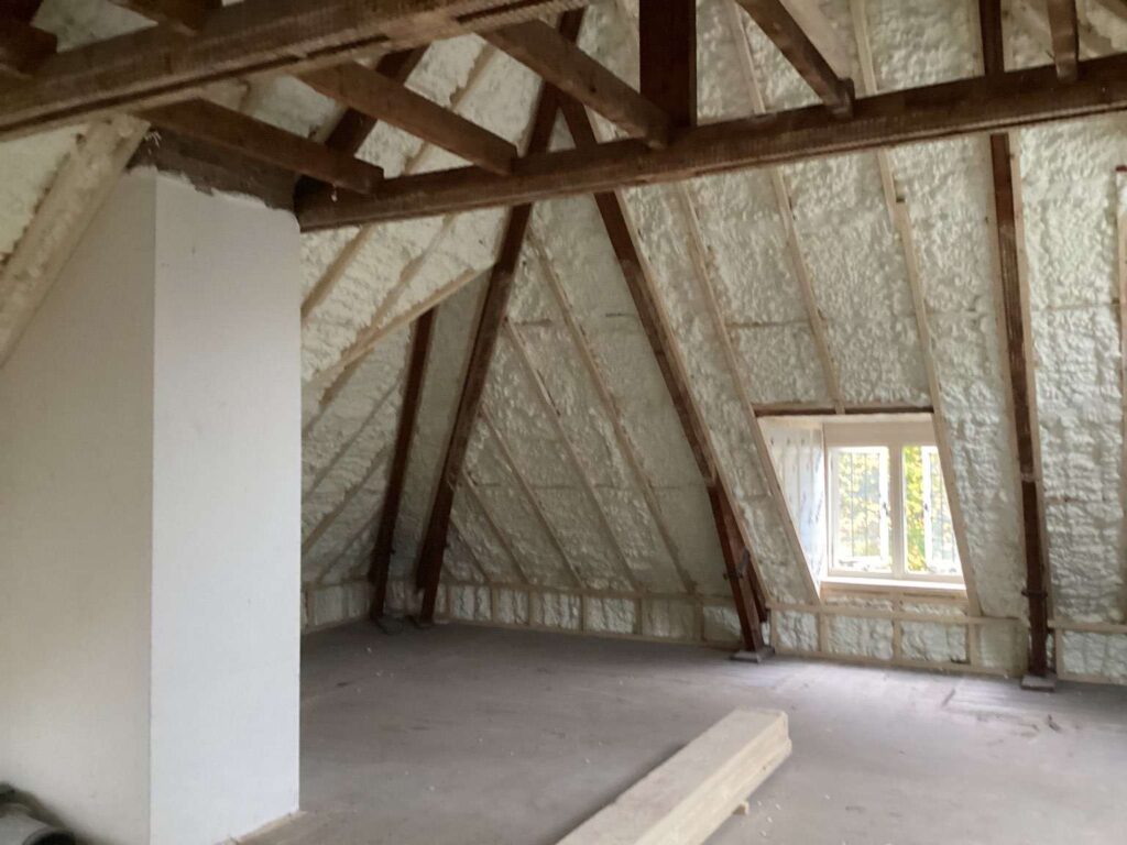 Dakisolatie aan de binnenzijde van een houten kap met zichtbare balken